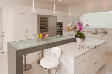 Mid-sized trendy l-shaped porcelain tile eat-in kitchen photo in New Orleans with an undermount sink, flat-panel cabinets, white cabinets, granite countertops, white backsplash, glass sheet backsplash, paneled appliances and an island