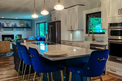Kitchen - large shabby-chic style single-wall light wood floor and brown floor kitchen idea in Other with a farmhouse sink, shaker cabinets, white cabinets, quartz countertops, stainless steel appliances, an island and white countertops