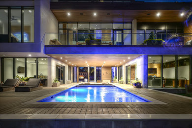 Example of a mid-sized trendy courtyard rectangular infinity pool design in Jacksonville with decking