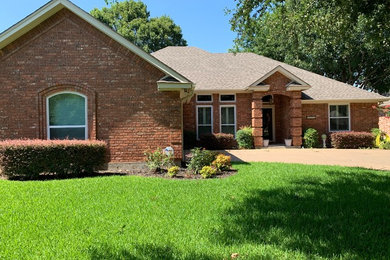 Example of a mid-sized brown one-story brick house exterior design in Dallas with a hip roof and a shingle roof