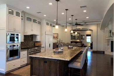 Inspiration for a large timeless single-wall dark wood floor and brown floor open concept kitchen remodel in Los Angeles with an undermount sink, raised-panel cabinets, white cabinets, granite countertops, multicolored backsplash, stone slab backsplash, paneled appliances, an island and multicolored countertops