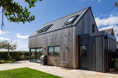 Inspiration for a large modern two-storey multi-coloured house exterior in Oxfordshire with wood siding, a gable roof, a metal roof and a black roof.
