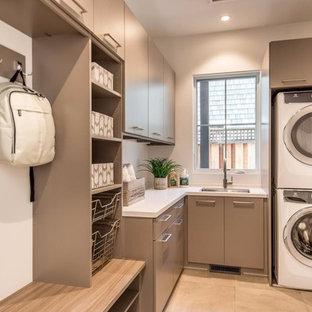 Inspiration for a medium sized modern l-shaped separated utility room in San Francisco with a submerged sink, flat-panel cabinets, brown cabinets, engineered stone countertops, white walls, porcelain flooring, a stacked washer and dryer, beige floors and white worktops.
