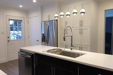 Inspiration for a mid-sized modern galley medium tone wood floor and brown floor eat-in kitchen remodel in Vancouver with a drop-in sink, flat-panel cabinets, white cabinets, quartz countertops, stainless steel appliances and an island
