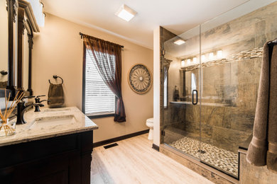 Photo of a large traditional master wet room bathroom in Chicago with beaded inset cabinets, dark wood cabinets, a one-piece toilet, multi-coloured tile, ceramic tile, beige walls, light hardwood floors, an undermount sink, engineered quartz benchtops, brown floor, a hinged shower door, multi-coloured benchtops, a shower seat, a double vanity and a built-in vanity.