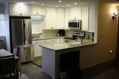 Inspiration for a mid-sized timeless u-shaped porcelain tile and gray floor eat-in kitchen remodel in Miami with an undermount sink, raised-panel cabinets, white cabinets, stainless steel appliances and a peninsula