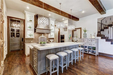 Inspiration for a transitional single-wall open plan kitchen in Orange County with a farmhouse sink, raised-panel cabinets, white cabinets, marble benchtops, multi-coloured splashback, stainless steel appliances, dark hardwood floors and with island.