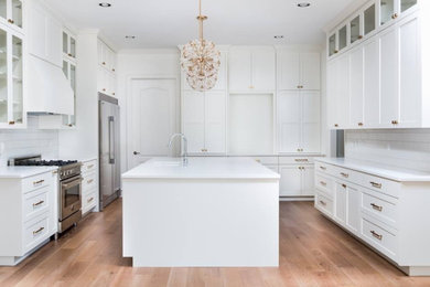 Inspiration for a large contemporary u-shaped eat-in kitchen in Austin with shaker cabinets, white cabinets, quartz benchtops, stainless steel appliances, medium hardwood floors, with island and white benchtop.