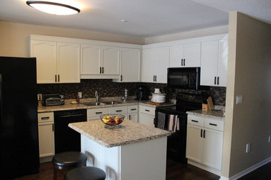 Example of a small trendy l-shaped dark wood floor kitchen pantry design in Calgary with a double-bowl sink, recessed-panel cabinets, gray cabinets, laminate countertops, brown backsplash, mosaic tile backsplash, black appliances and an island