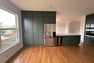 Inspiration for a large contemporary u-shaped medium tone wood floor, beige floor and vaulted ceiling eat-in kitchen remodel in Denver with a farmhouse sink, shaker cabinets, green cabinets, quartzite countertops, white backsplash, marble backsplash, stainless steel appliances, two islands and white countertops
