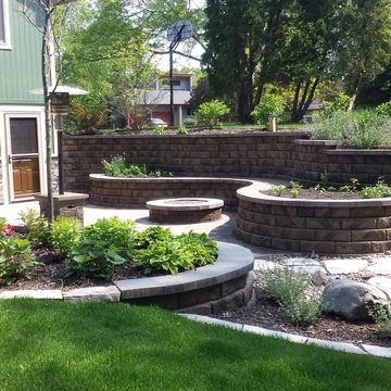 Backyard patio with gas fire pit, retaining walls and full landscape.