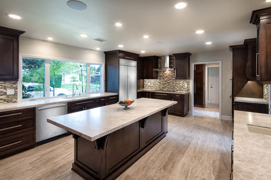 This is an example of an expansive transitional u-shaped open plan kitchen in Orange County with an undermount sink, shaker cabinets, dark wood cabinets, quartzite benchtops, grey splashback, glass tile splashback, stainless steel appliances, porcelain floors, with island and beige floor.