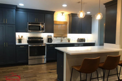 Example of a mid-sized transitional galley medium tone wood floor open concept kitchen design in Other with an undermount sink, shaker cabinets, blue cabinets, quartzite countertops, white backsplash, ceramic backsplash, stainless steel appliances, a peninsula and white countertops