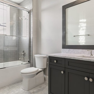 Ispirazione per una stanza da bagno con doccia costiera di medie dimensioni con ante in stile shaker, ante grigie, vasca ad alcova, WC monopezzo, piastrelle grigie, piastrelle diamantate, pareti grigie, pavimento in marmo, lavabo sottopiano, top in marmo, porta doccia scorrevole, top bianco, vasca/doccia e pavimento bianco