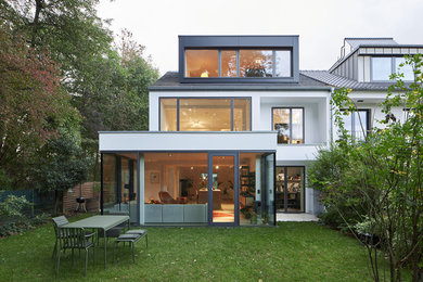 Design ideas for a mid-sized modern white townhouse exterior in Cologne with a gable roof and a tile roof.