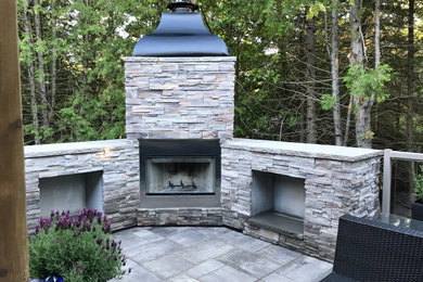 This is an example of a large contemporary backyard patio in Toronto with with fireplace, concrete pavers and a roof extension.