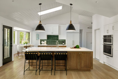 Inspiration for a large transitional l-shaped medium tone wood floor, brown floor and shiplap ceiling open concept kitchen remodel in Minneapolis with an undermount sink, recessed-panel cabinets, white cabinets, quartz countertops, green backsplash, ceramic backsplash, stainless steel appliances, an island and white countertops