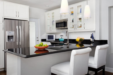 Small transitional u-shaped dark wood floor enclosed kitchen photo in DC Metro with shaker cabinets, white cabinets, stainless steel appliances, an undermount sink, quartz countertops and a peninsula