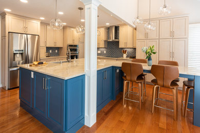 This is an example of a medium sized traditional l-shaped kitchen/diner in Denver with a single-bowl sink, flat-panel cabinets, blue cabinets, quartz worktops, blue splashback, porcelain splashback, stainless steel appliances, medium hardwood flooring, an island, brown floors, beige worktops and a vaulted ceiling.