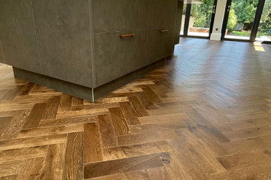 Large contemporary kitchen/diner in Sussex with dark hardwood flooring and an island.