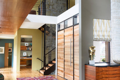 Photo of a contemporary foyer in Denver with green walls, medium hardwood floors, a single front door, a medium wood front door and brown floor.