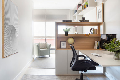 Modelo de despacho actual con paredes blancas, suelo de madera en tonos medios y escritorio empotrado