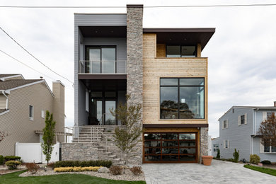 Imagen de fachada de casa multicolor y marrón contemporánea de tamaño medio de tres plantas con revestimientos combinados, tejado plano y tablilla