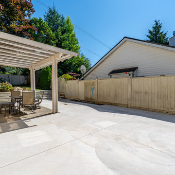 Large Concrete Backyard Patio and Pergola Seating Area – Coquitlam Renovation