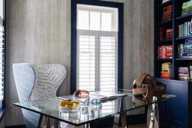 This is an example of a transitional home office in New York with beige walls, light hardwood floors, wallpaper and wood walls.