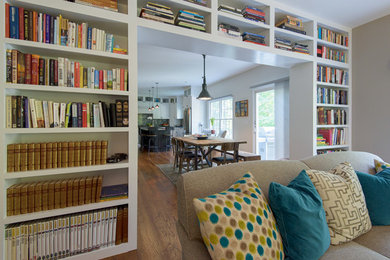 Photo of a mid-sized transitional enclosed living room in New York with a library, grey walls, dark hardwood floors and no tv.