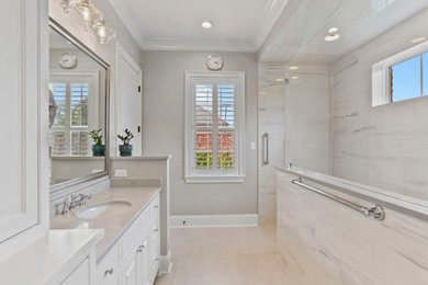 Example of a large transitional master multicolored tile and marble tile porcelain tile, white floor and double-sink bathroom design in New Orleans with white cabinets, a two-piece toilet, beige walls, an undermount sink, quartz countertops, gray countertops, a built-in vanity and raised-panel cabinets