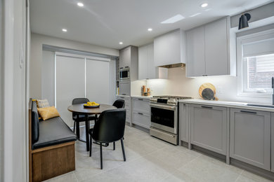 Mid-sized minimalist l-shaped porcelain tile and gray floor eat-in kitchen photo in Toronto with an undermount sink, beige cabinets, quartz countertops, white backsplash, quartz backsplash, stainless steel appliances and white countertops