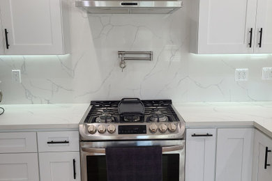Inspiration for a mid-sized coastal medium tone wood floor and coffered ceiling kitchen remodel in Los Angeles with marble countertops and stainless steel appliances