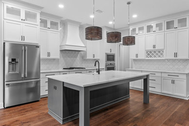 Open concept kitchen - mid-sized traditional l-shaped dark wood floor and brown floor open concept kitchen idea in Other with an undermount sink, recessed-panel cabinets, white cabinets, white backsplash, stainless steel appliances, an island, white countertops and quartz countertops