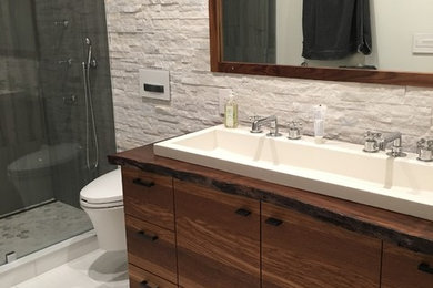 Example of a large minimalist 3/4 white tile and stone tile porcelain tile, white floor and double-sink alcove shower design in Boston with flat-panel cabinets, brown cabinets, a wall-mount toilet, white walls, a trough sink, wood countertops, a hinged shower door, brown countertops, a niche and a floating vanity