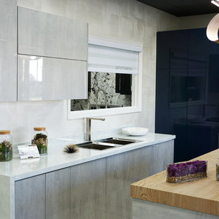 Kleine Moderne Küche in U-Form mit Vorratsschrank, Doppelwaschbecken, flächenbündigen Schrankfronten, Schränken im Used-Look, Quarzit-Arbeitsplatte, Küchenrückwand in Weiß, Rückwand aus Stein, Küchengeräten aus Edelstahl, Laminat, Kücheninsel, braunem Boden und weißer Arbeitsplatte in Miami