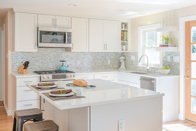 Small transitional l-shaped medium tone wood floor eat-in kitchen photo in Boston with an undermount sink, flat-panel cabinets, white cabinets, quartz countertops, multicolored backsplash, stainless steel appliances, an island and white countertops