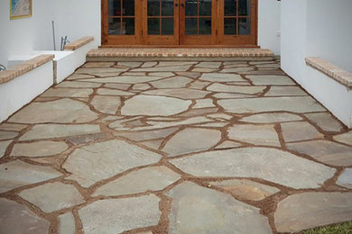 Example of a large mountain style front yard stone patio design in Toronto with no cover