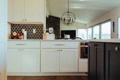 Example of a large beach style medium tone wood floor and brown floor kitchen design in Seattle with an undermount sink, recessed-panel cabinets, white cabinets, quartz countertops, blue backsplash, ceramic backsplash, stainless steel appliances, an island and white countertops