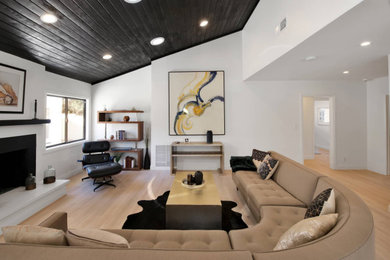 Inspiration for a large 1950s light wood floor and shiplap ceiling family room remodel in Los Angeles with white walls, a standard fireplace and a stone fireplace