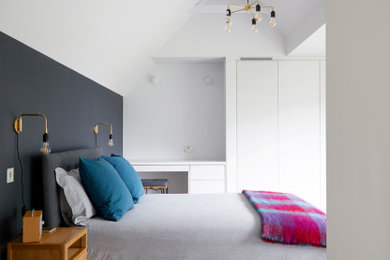This is an example of a medium sized classic guest and grey and white loft bedroom in London with white walls, medium hardwood flooring, no fireplace, multi-coloured floors and a vaulted ceiling.