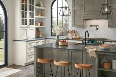 Large elegant u-shaped dark wood floor and brown floor kitchen photo in Other with a single-bowl sink, flat-panel cabinets, medium tone wood cabinets, quartz countertops, white backsplash, mosaic tile backsplash, black appliances, an island and black countertops