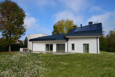 Imagen de fachada de casa negra actual grande de dos plantas con revestimiento de estuco, tejado a cuatro aguas y tejado de metal