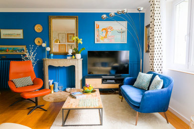 Cette photo montre un grand salon tendance ouvert et haussmannien avec une salle de réception, un mur bleu, un sol en bois brun, une cheminée standard et un sol beige.