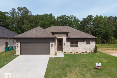 Mid-sized minimalist brown one-story brick house exterior photo in Little Rock with a shingle roof and a brown roof