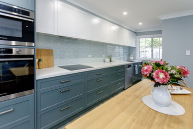 Inspiration for a mid-sized transitional open plan kitchen in Sydney with green cabinets, green splashback, stainless steel appliances and brown floor.