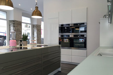 Offene Moderne Küche mit Glas-Arbeitsplatte, Küchenrückwand in Weiß, Glasrückwand, Küchengeräten aus Edelstahl und Kücheninsel in Sonstige