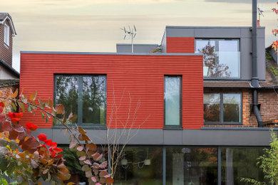 Inspiration for a medium sized and red contemporary rear house exterior in Hampshire with three floors, wood cladding and a flat roof.