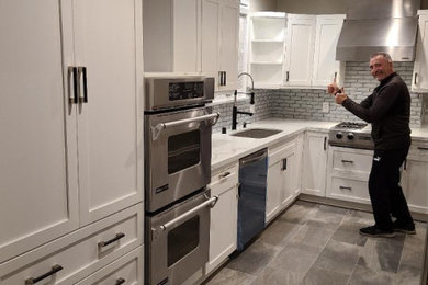 Mid-sized minimalist galley slate floor and gray floor kitchen photo in Los Angeles with an undermount sink, shaker cabinets, white cabinets, quartzite countertops, metallic backsplash, glass tile backsplash, stainless steel appliances, an island and white countertops