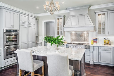 Mid-sized elegant u-shaped dark wood floor eat-in kitchen photo in Los Angeles with a double-bowl sink, recessed-panel cabinets, gray cabinets, granite countertops, white backsplash, subway tile backsplash, stainless steel appliances and an island